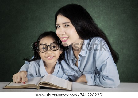 Picture of young female teacher with her student learning together while sitting in the classroom