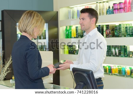 smiling woman is paying after hair treatment