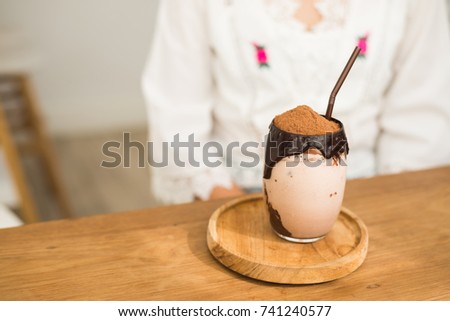 A glass of cocoa Frappe or Cocoa shake with brown Straws