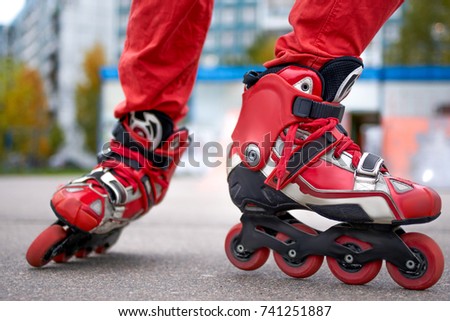 on roller skates in a skate sport park with a bright background of bright red rollers. Red bright colors
