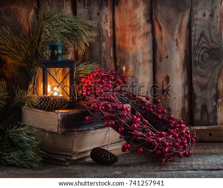 Christmas wreath on books with a lantern on the wooden background. Horizontal view. Toned.