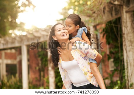 Mother giving piggyback ride to her loving daughter
