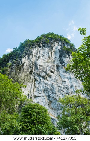 Stone mountain covered in green nature with blue sky