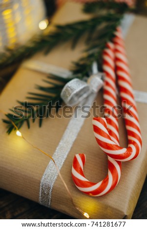 Christmas present with candy canes and Fir tree branch on dark wooden background. Selective focus