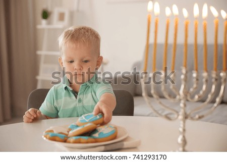 Jewish boy eating festive Hanukkah cookies at home