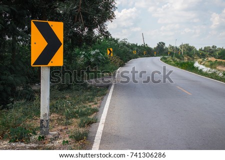 Road signs indicating right turn while driving with yellow sign reflecting light to be visible at night in the countryside of Thailand
