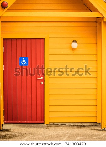 Blue handicapped wheelchair sign on door of public toilet outdoor, WC restroom