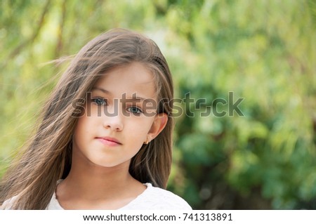 Sweet little girl in the park, with long hair and and a sweet, gentle look.  Happy childhood concept. 