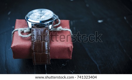 Gift watch  on a dark background concept of a holiday
