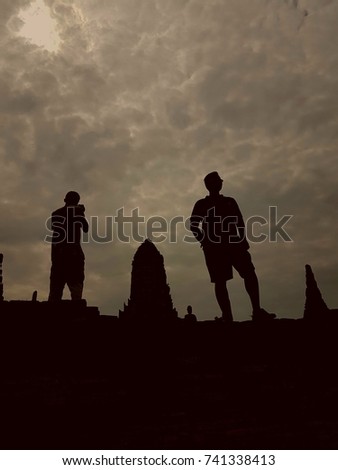 Silhouette photo of male tourists exploring ancient temple in Thailand.