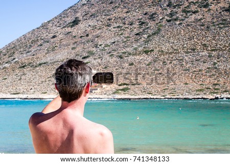 Man photographing sea and mountains in Crete, Greece