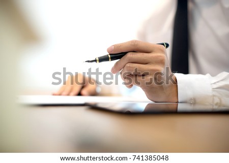 Business man hold pen on the air white mode blur background more copyspace Royalty-Free Stock Photo #741385048