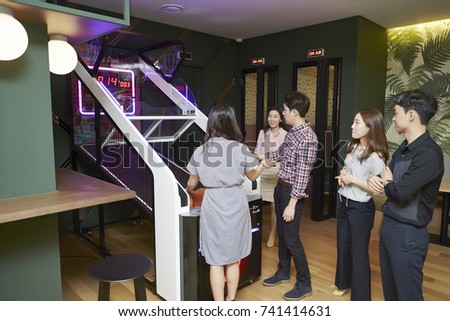 Korean man and woman playing basketball arcade game 