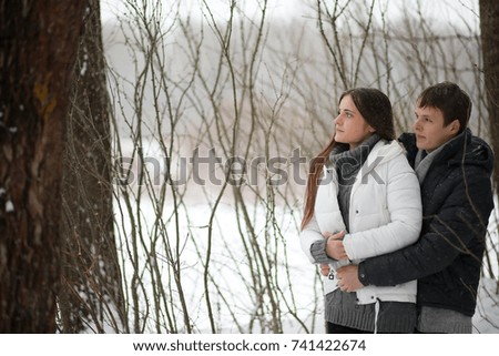 A pair of lovers on a date winter afternoon in a snow blizzard. girl on a winter sunny afternoon for a walk a winter snow-covered park. Couple the street the winter in a down jacket

