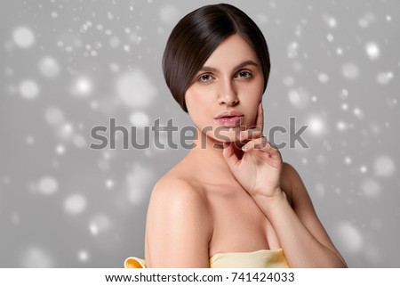 Beauty Woman face Portrait. Beautiful Spa model Girl with Perfect Fresh Clean Skin. Brunette female  Snow snowflakes background winter
