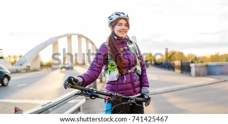 Image of sports woman in helmet on bicycle on bridge in city