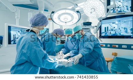 Medical Team Performing Surgical Operation in Bright Modern Operating Room Royalty-Free Stock Photo #741433855