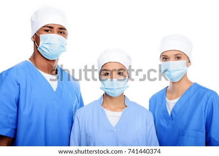 multiethnic surgeons in medical masks and caps, isolated on white