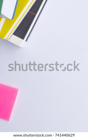 A white background texture with some colorful books in a corner and a post it. Can be vertical or horizontal 