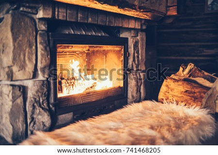 Warm cozy fireplace with real wood burning in it. Cozy winter concept. Christmas and travel background with space for your text.