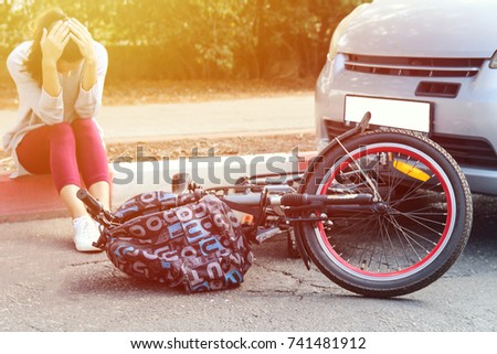 A woman holding her head near a traffic accident between electric ebike and car