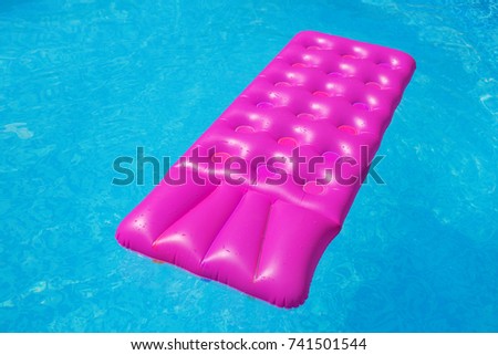 Pink air mattress on a swimming pool - holiday tropical background concept