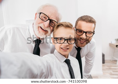 Father, son and grandfather wearing formal clothing and glasses taking a selfie Royalty-Free Stock Photo #741530398