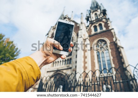 Person with smart phone makes pictures of beautiful old city church