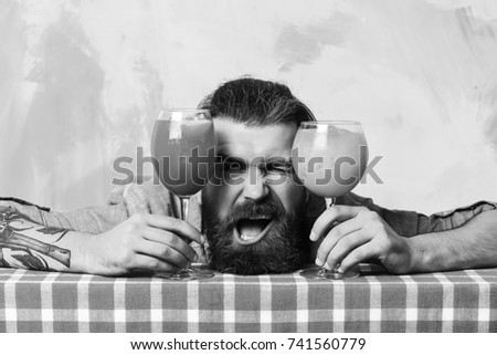 Bearded man, long beard. Brutal caucasian smiling happy hipster with moustache in denim shirt between tropical alcoholic fresh cocktails on blue checkered plaid on colorful texture background