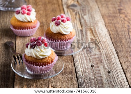 Candied cranberries and cream cheese  homemade cupcakes on wooden board. Homemade autumn holiday dessert on  rustic table