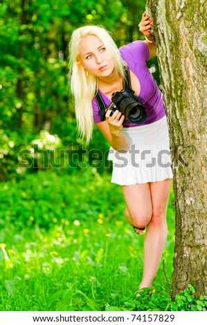 young woman with camera looking for object 	
