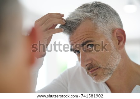 40-year-old man checking hair in front of mirror Royalty-Free Stock Photo #741581902