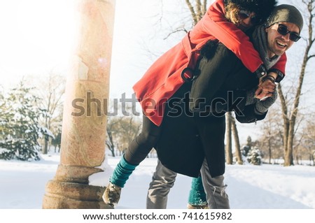 Happy couple on winter vacation. Man giving woman piggyback ride on snow. Love spending time with you