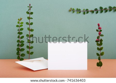 Horizontal greeting card standing on table surrounded by green plants