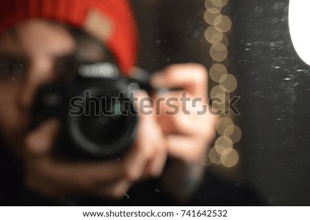 Blur art photography reflection in the mirror of a person talking a photograph with a black professional camera with lights on the background