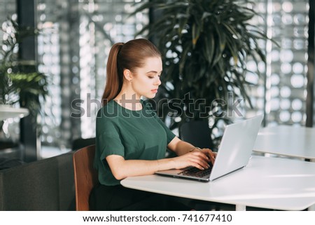 beautiful business lady at work with a laptop and phone sitting in the office