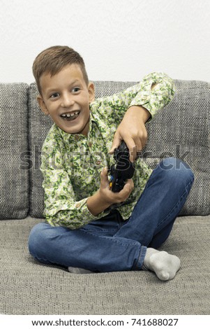 Boy playing video games with joystick sitting on sofa