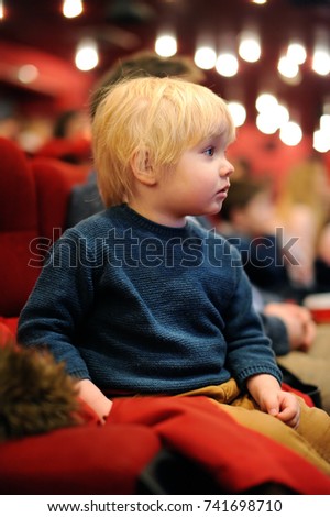 Cute toddler boy watching cartoon movie in the cinema. Leisure entertainment for family with kids.