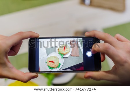 Hands with phone close-up photography food. Two hamburgers with hot peppers