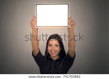 Grateful letter. Gratitude concept. Accolade. Thank letter. Special offer. Young business women in strict dress holding in hands empty blank photo frame above the head. Appreciation document.