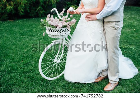 Pretty young bride and groom with retro bike in a green park