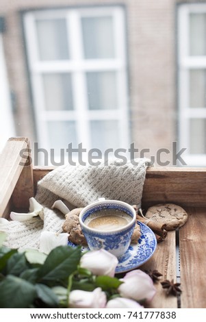 coffee in a vintage cup, on a wooden background and a bouquet of white roses. City outside the window