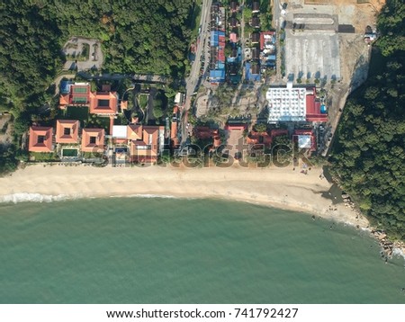 Aerial view of ocean waves crashing on beach with tourists relaxing, walking and swimming at the beach