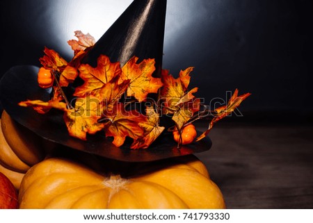 autumn holiday, a large pumpkin, golden leaves on a black witch hat. Halloween, a mesmerizing picture