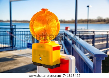 Signal alarm flashlight on guardrail of sea pier.