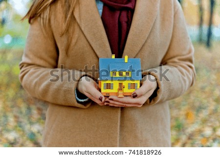 Mini yellow house model in woman hands. ?ozy home concept