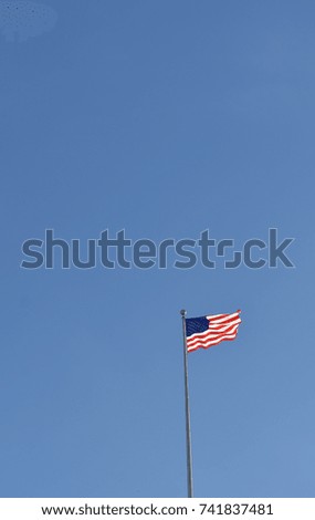 American Flag on pole above United States Capital Building with clear blue sky and copy space
