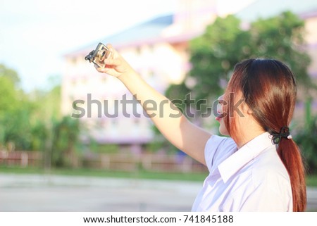 Portrait of a smiling and cheerful asian woman making selfie photo on smartphone.