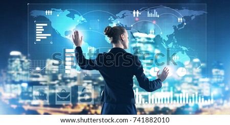 Back view of businesswoman working with virtual panel and night city at background