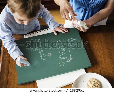 Little boy drawing dinosaurs with chalk